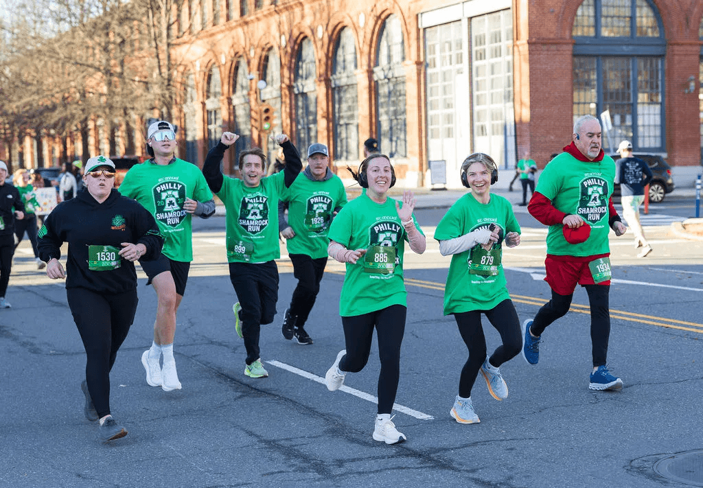 Happy Philly Shamrock Run participants running through Navy Yard, South Philadelphia, in green race shirts